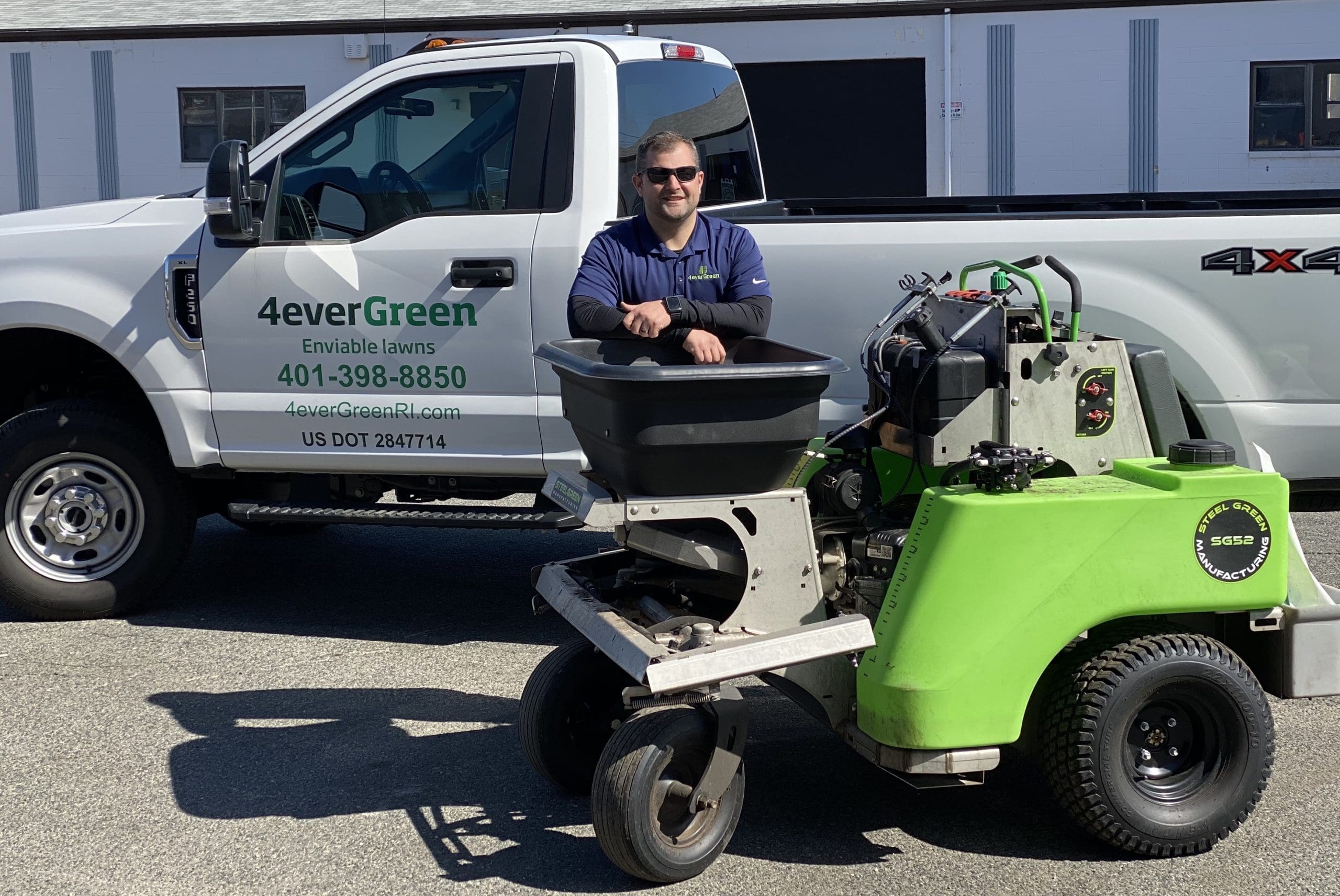 Lawn care technician applying pre-emergent weed control to Attleboro lawn in spring