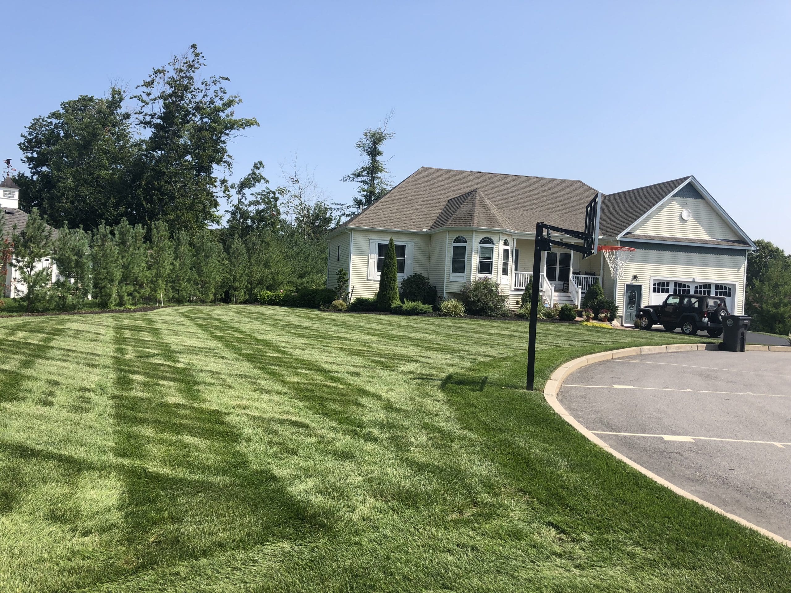 Spreader applying late summer fertilizer across a lush green lawn